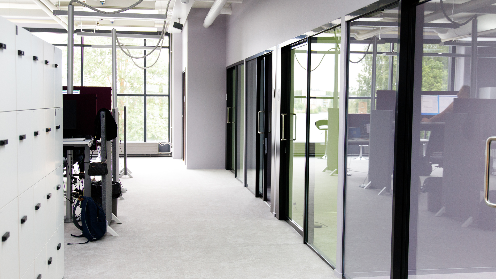 Tässä on kuva Meitan toimiston käytävästä, jossa on ovia neuvotteluhuoneisiin sekä näkyy toisella sivulla työskentelypisteitä
