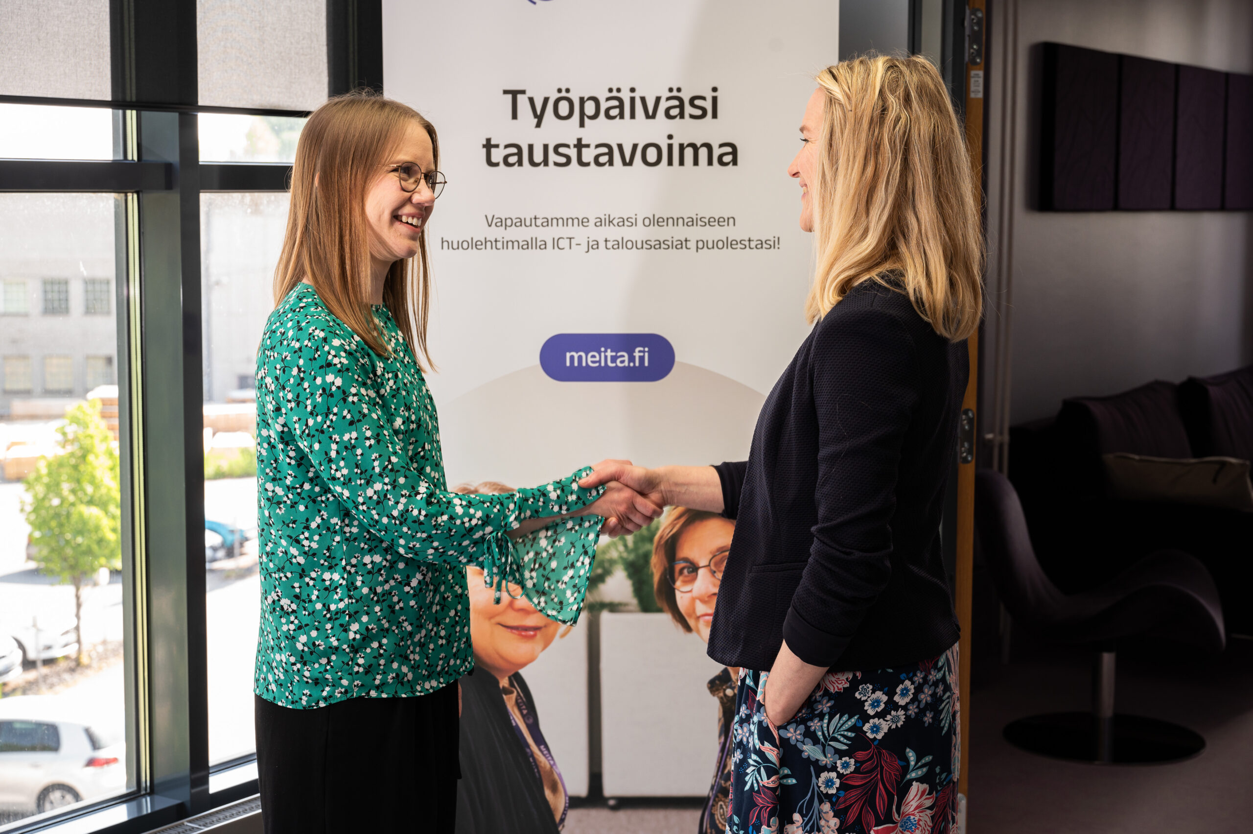 Tässä kuvassa seisoo kaksi hymyilevää ja kättelevää meitalaista