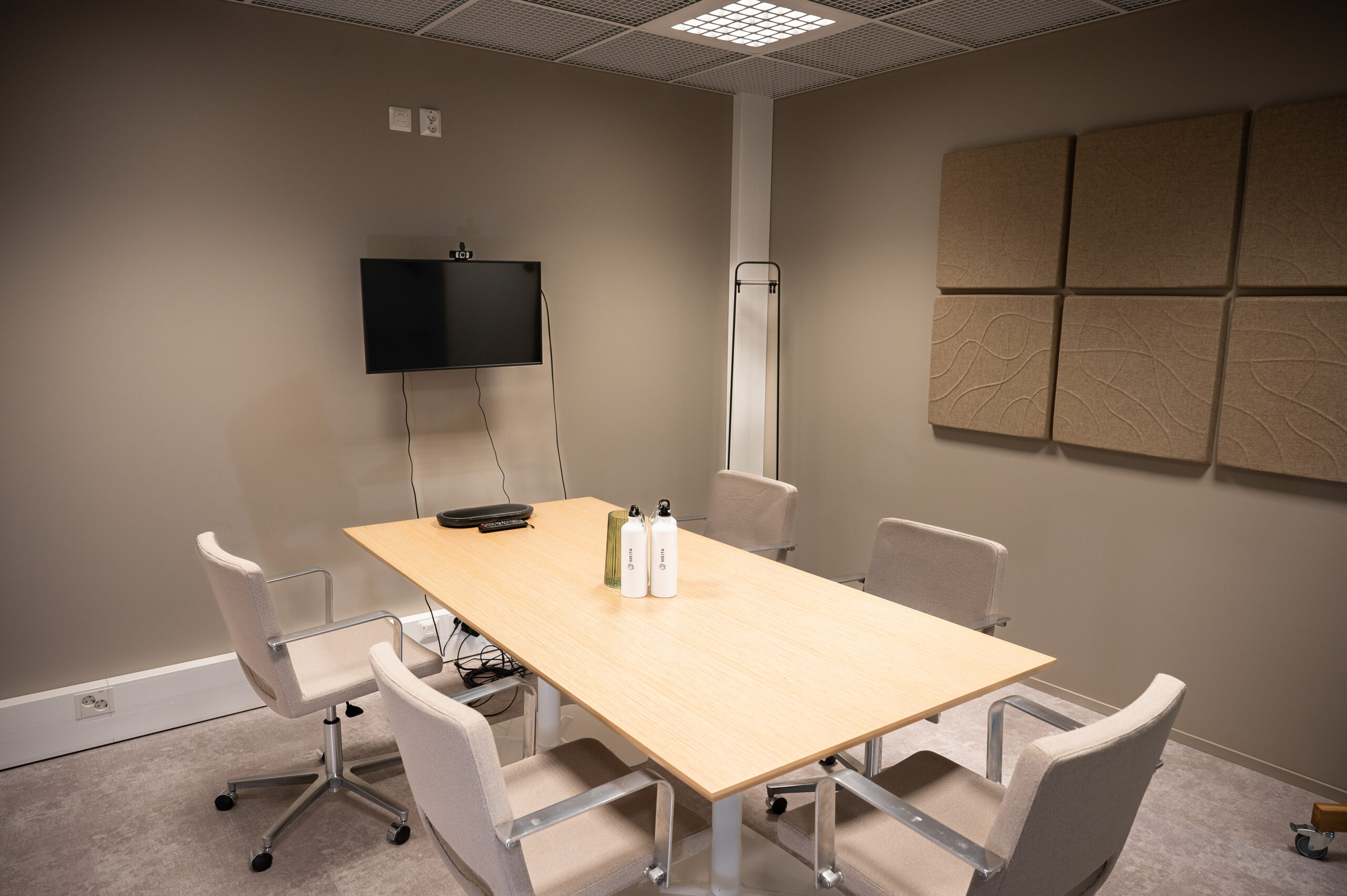 Tässä kuvassa on yksi Meitan toimiston neuvotteluhuoneista, jossa on pöytä tuoleineen sekä seinällä näyttö ja äänieristelevyt